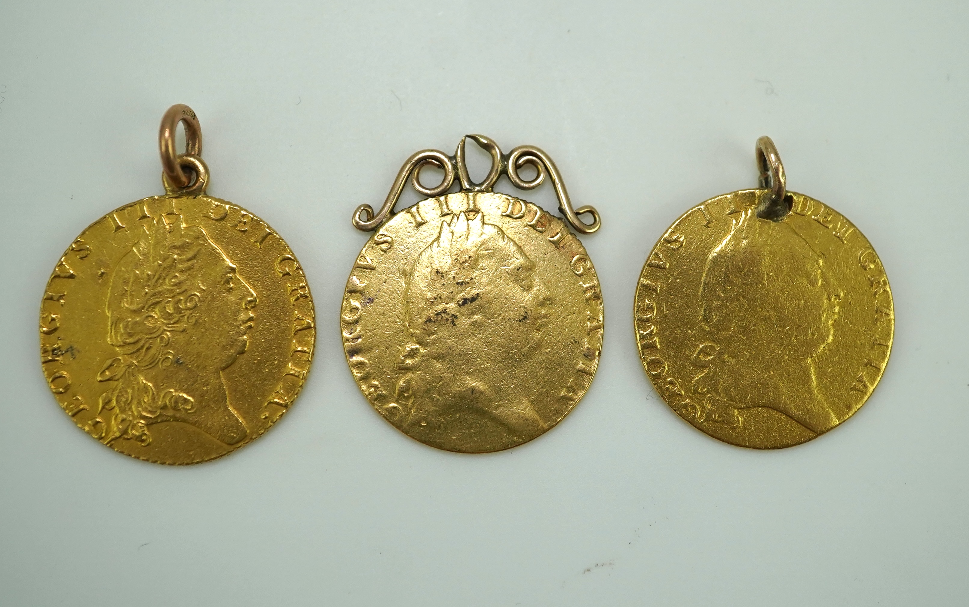 Three George III gold spade guinea coin pendants, late 18th/early 19th century and later